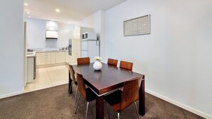 A modern kitchen with white cabinets, a microwave, and a small refrigerator. - Spacious 2BR Near Westfield Newmarket (Auckland)