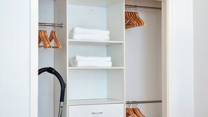 A white closet with wooden hangers and a vacuum cleaner. - Spacious 2BR Near Westfield Newmarket (Auckland)