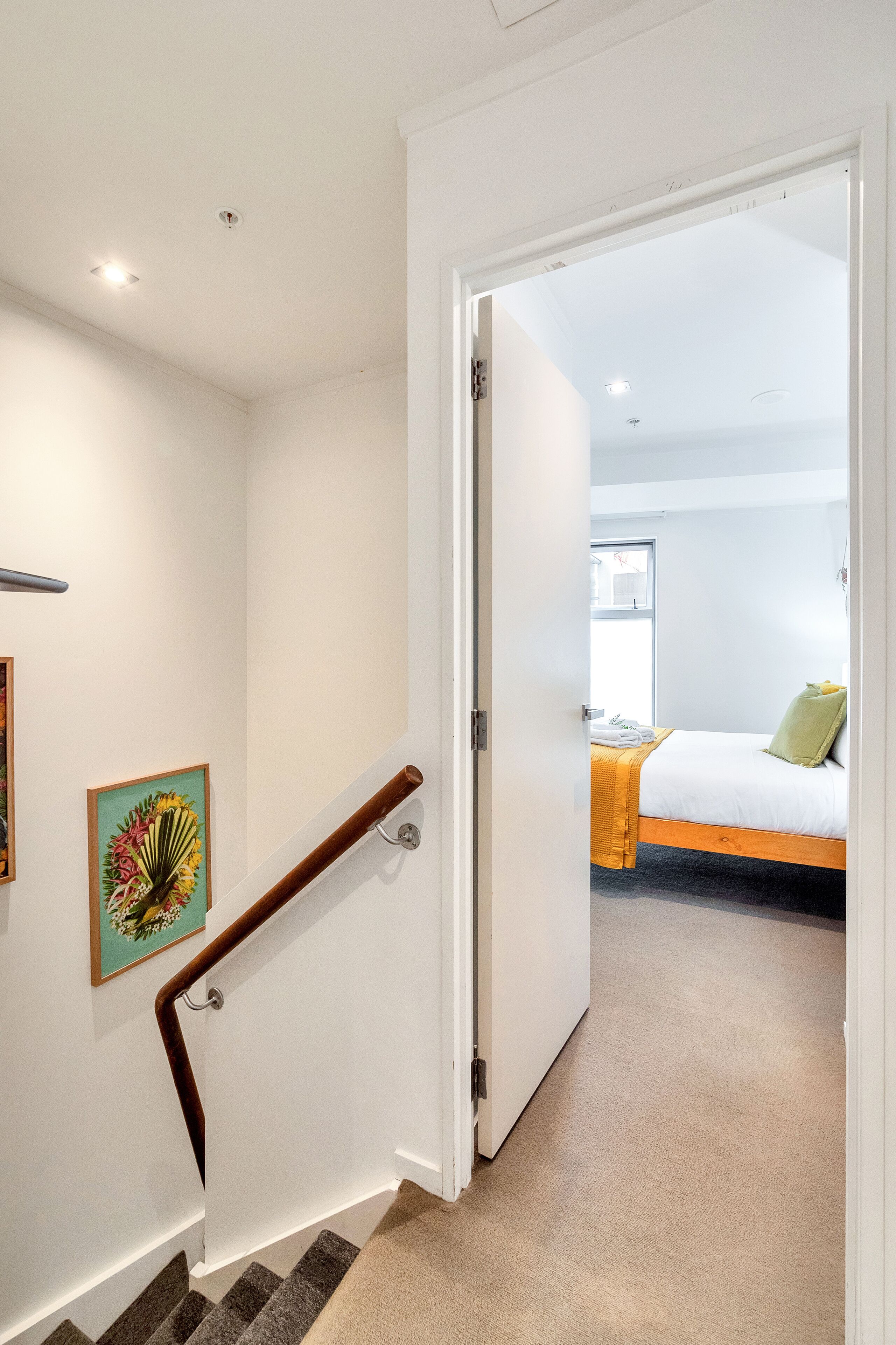 Un couloir menant à une chambre à coucher, qui contient un lit, une fenêtre et une porte.
