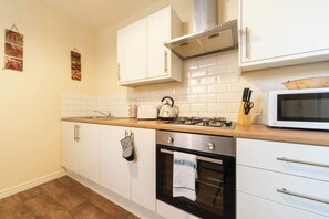 A kitchen with white cabinets, a microwave, a stove, and a sink.