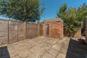 A fenced backyard with a brick structure, possibly a shed, and a wooden fence.