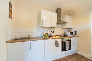 A kitchen with white cabinets, a stainless steel sink, a microwave, and a stove.