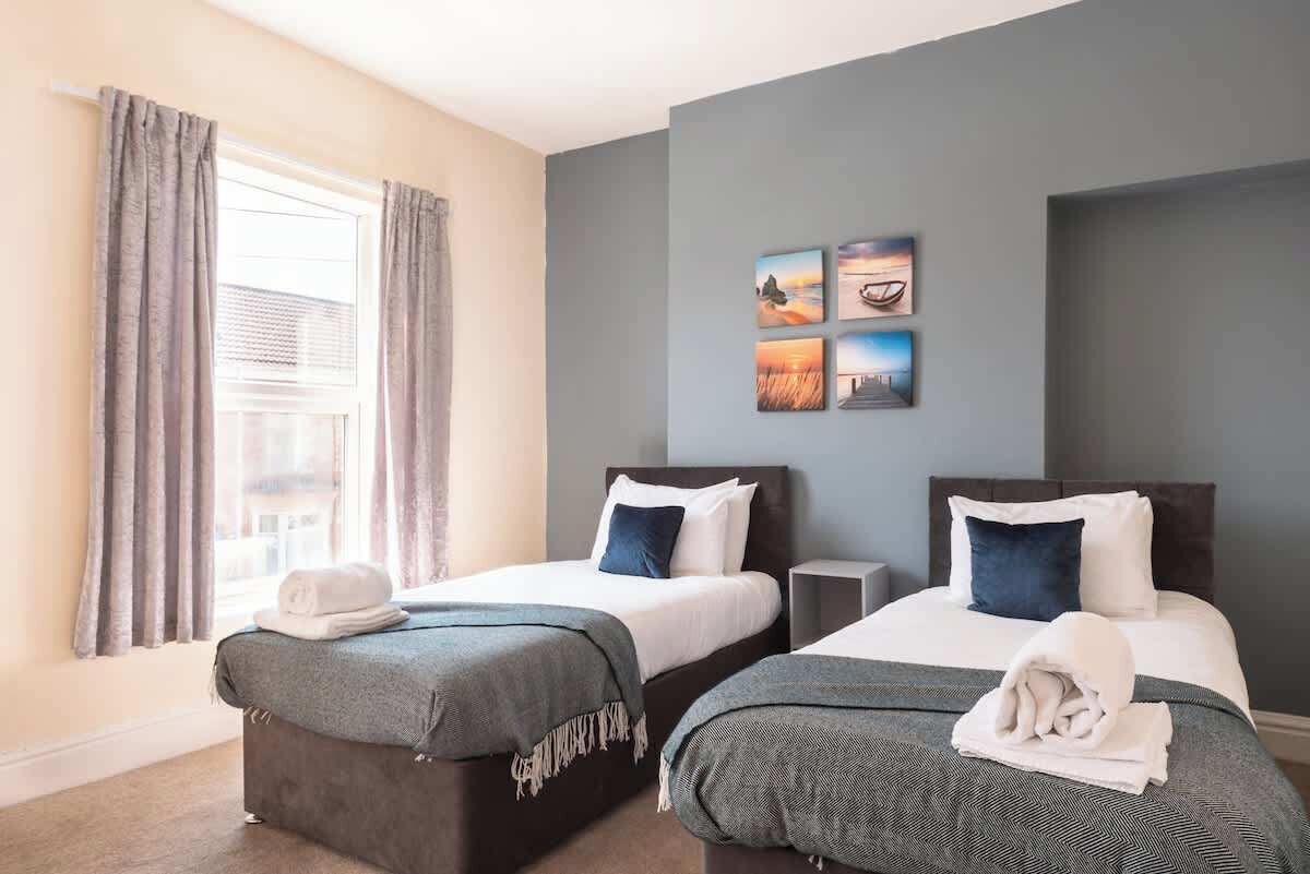 A hotel room with two beds, a window with curtains, and wall art.