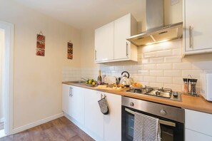 A modern kitchen with white cabinets, a stainless steel stove, and a tiled backsplash.