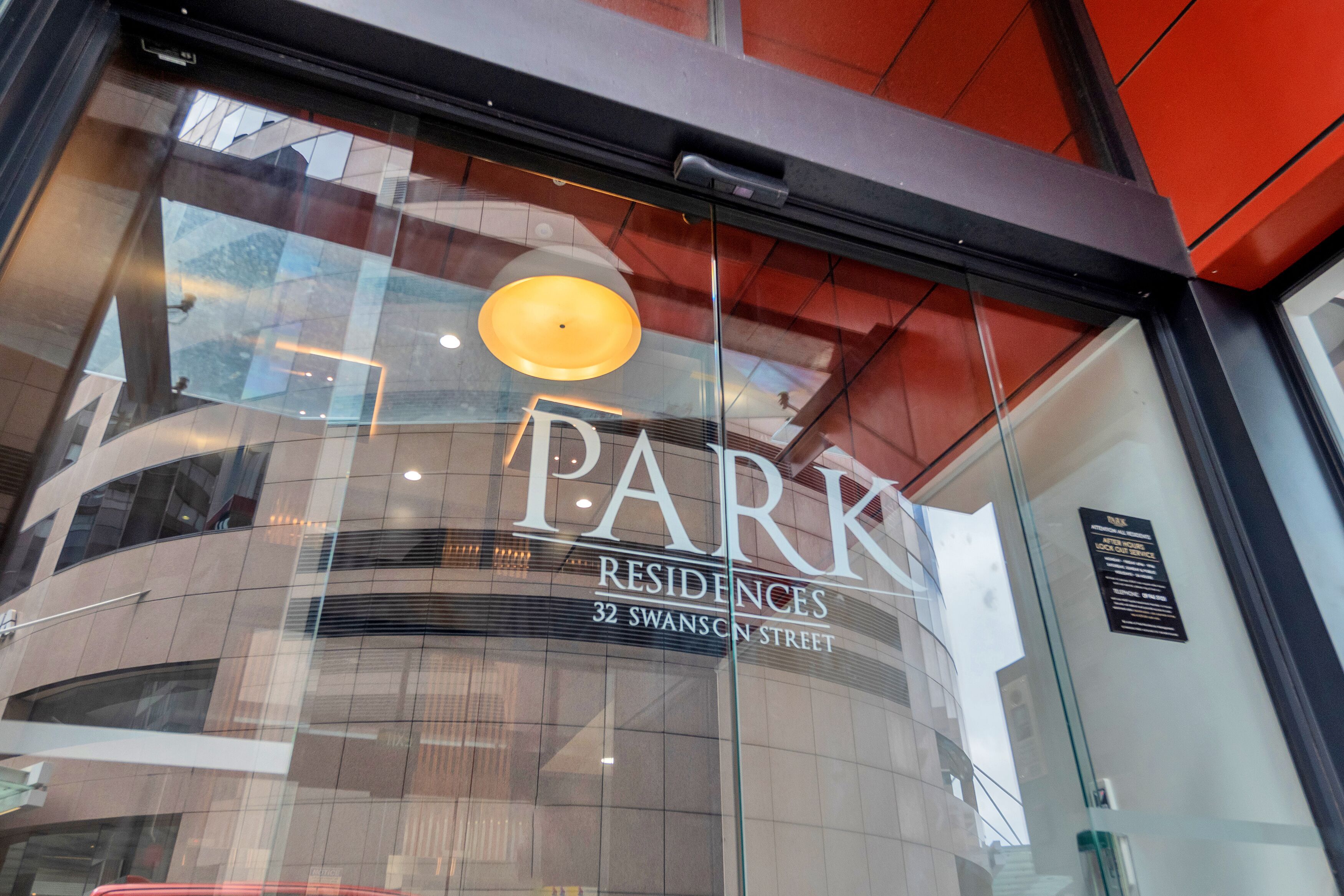 Un bâtiment moderne doté d’une façade en verre, sur lequel on peut lire en grand le nom « PARK Residences ».