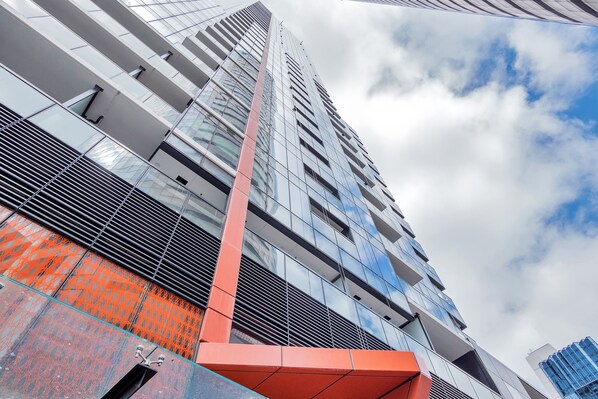 Een modern hoog gebouw met reflecterende glazen ramen en een opvallend rood structureel element.