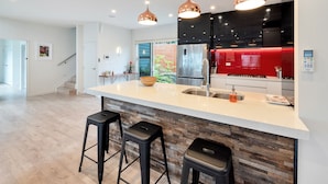 A modern kitchen with a large island, stainless steel appliances, and pendant lighting. - Elegant and Stylish Retreat in Epsom (Auckland)