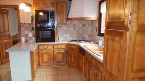 A kitchen with wooden cabinets, a central island, a microwave, and a stove.
