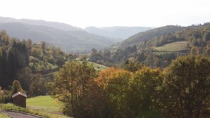 A rural landscape with rolling hills, a small wooden structure, and a road curving through the scene.