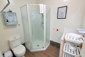 A modern bathroom with a glass-enclosed shower, a toilet, and a sink area with a towel rack. - Awesome City Studio with WiFi Nr Spark Arena (Auckland)