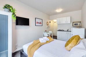 A hotel room with a bed, a desk, a chair, a television, a microwave, and a kitchenette. - Awesome City Studio with WiFi Nr Spark Arena (Auckland)