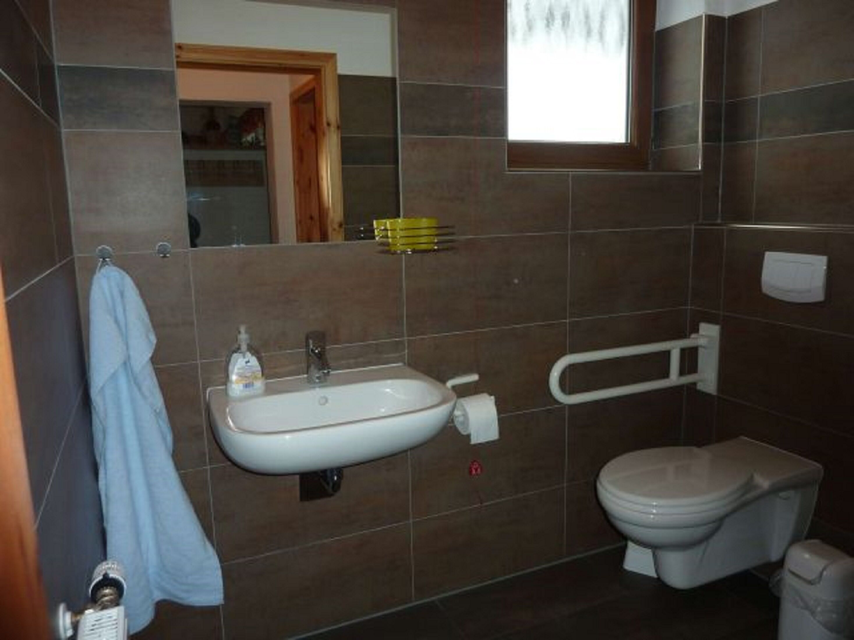 A bathroom with a sink, toilet, and a towel hanging on the wall.
