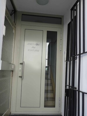 Een deur met de tekst 'APARTMENT AM KUHTURM' en een zicht op een wenteltrap binnen.