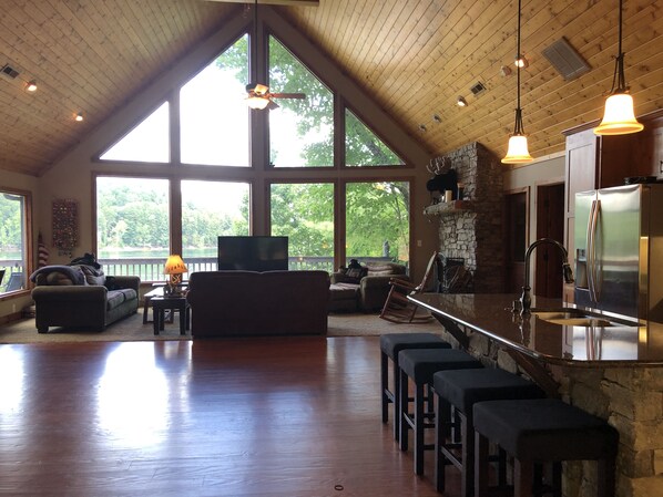Vaulted great room / living room with stone fireplace and incredible lake views!
