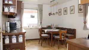 A cozy kitchen with wooden cabinets, a dining table, chairs, and a window with a view. - Ferienhaus Betty (Selbitz)
