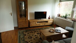 A living room with a wooden cabinet, a television, a coffee table, and a sofa. - Ferienhaus Betty (Selbitz)
