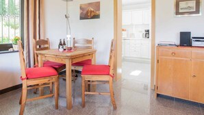 Un comedor con una mesa y sillas de madera, una lámpara y vistas a una cocina.
