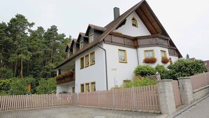 A two-story house with a steeply pitched roof, wooden balcony railings, and flower boxes on the windowsills. - Ferienwohnungen Lehner (Mitteleschenbach)