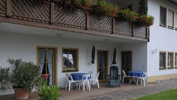 A building with a balcony, potted plants, and outdoor seating. - Ferienwohnungen Lehner (Mitteleschenbach)