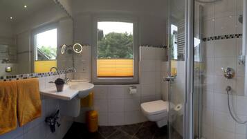 Baño con lavabo, espejo, inodoro y ducha.