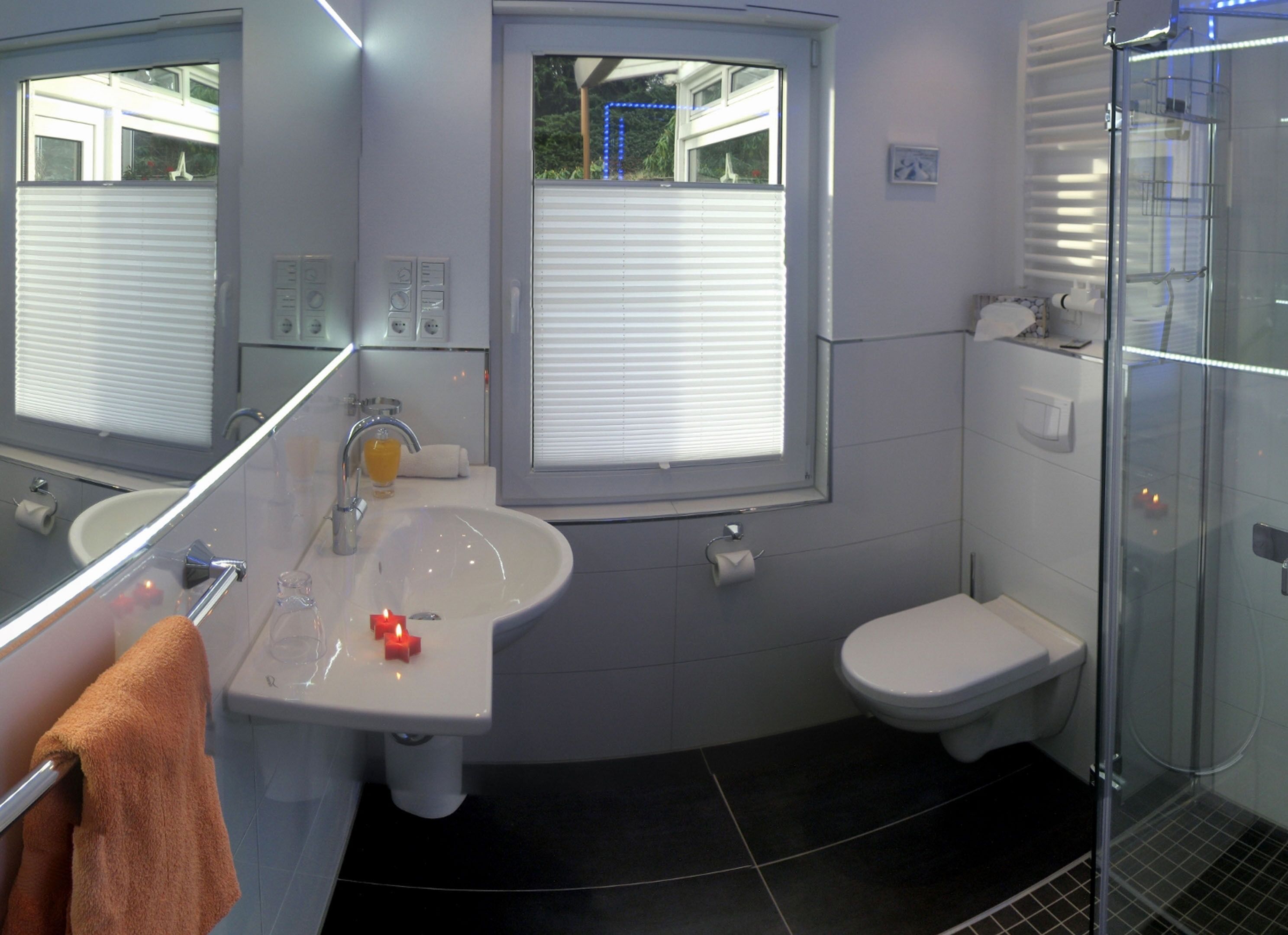 Un bagno moderno con lavandino bianco, un water e una cabina doccia in vetro.