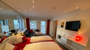 Una habitación de hotel moderna con una cama grande, un escritorio, una silla y un televisor montado en la pared.