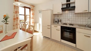 Una cocina con comedor, un refrigerador, una estufa y una cafetera.
