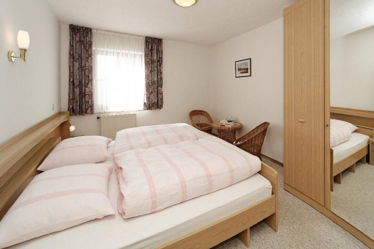 Une chambre à coucher avec un grand lit, une petite table avec des chaises, un radiateur et un miroir.