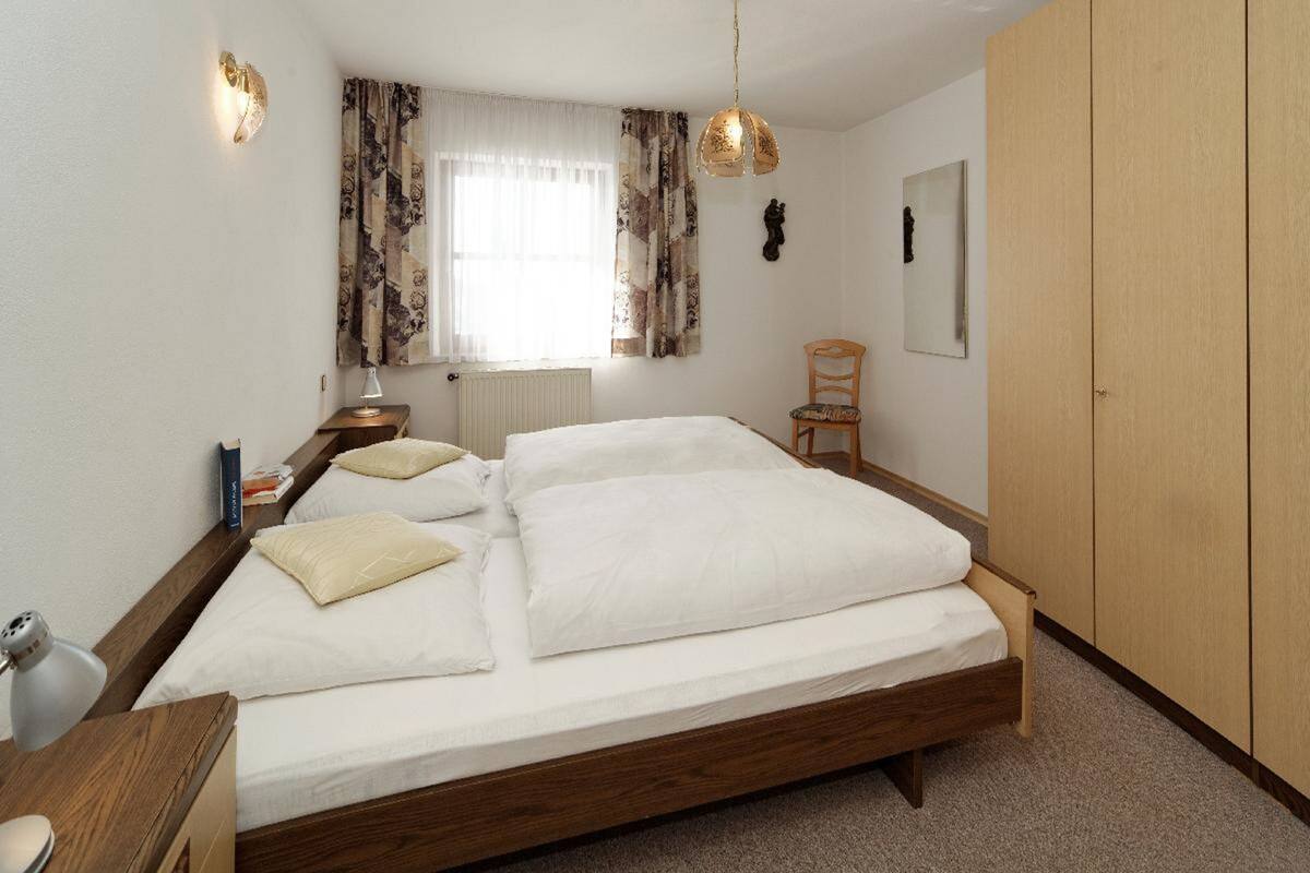 Une chambre à coucher avec un grand lit, une tête de lit en bois, un bureau avec une lampe, une chaise et une armoire.