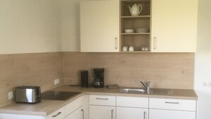 A compact kitchen with white cabinets, a stainless steel sink, a coffee maker, and a toaster.