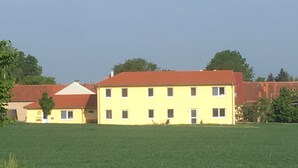 A yellow building with a red roof, surrounded by a green field.