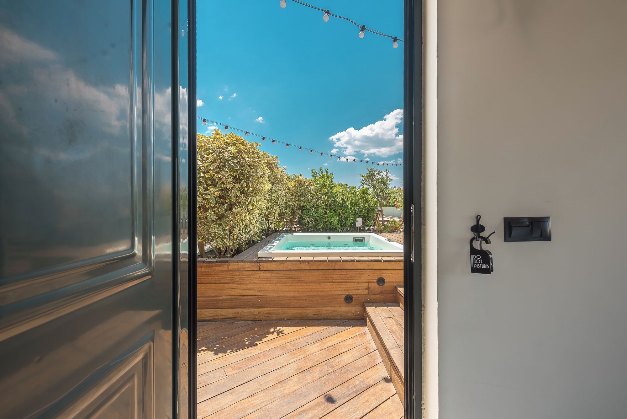 A wooden deck leading to a swimming pool with a clear blue sky above.