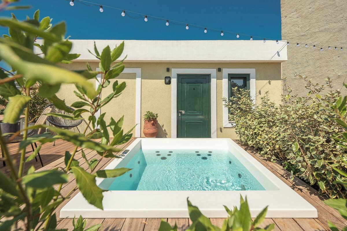 A swimming pool with a wooden deck, a green door, and string lights above.