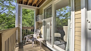 Une terrasse couverte avec deux chaises et une table, donnant sur un jardin avec une chaise et une autre chaise à motifs.