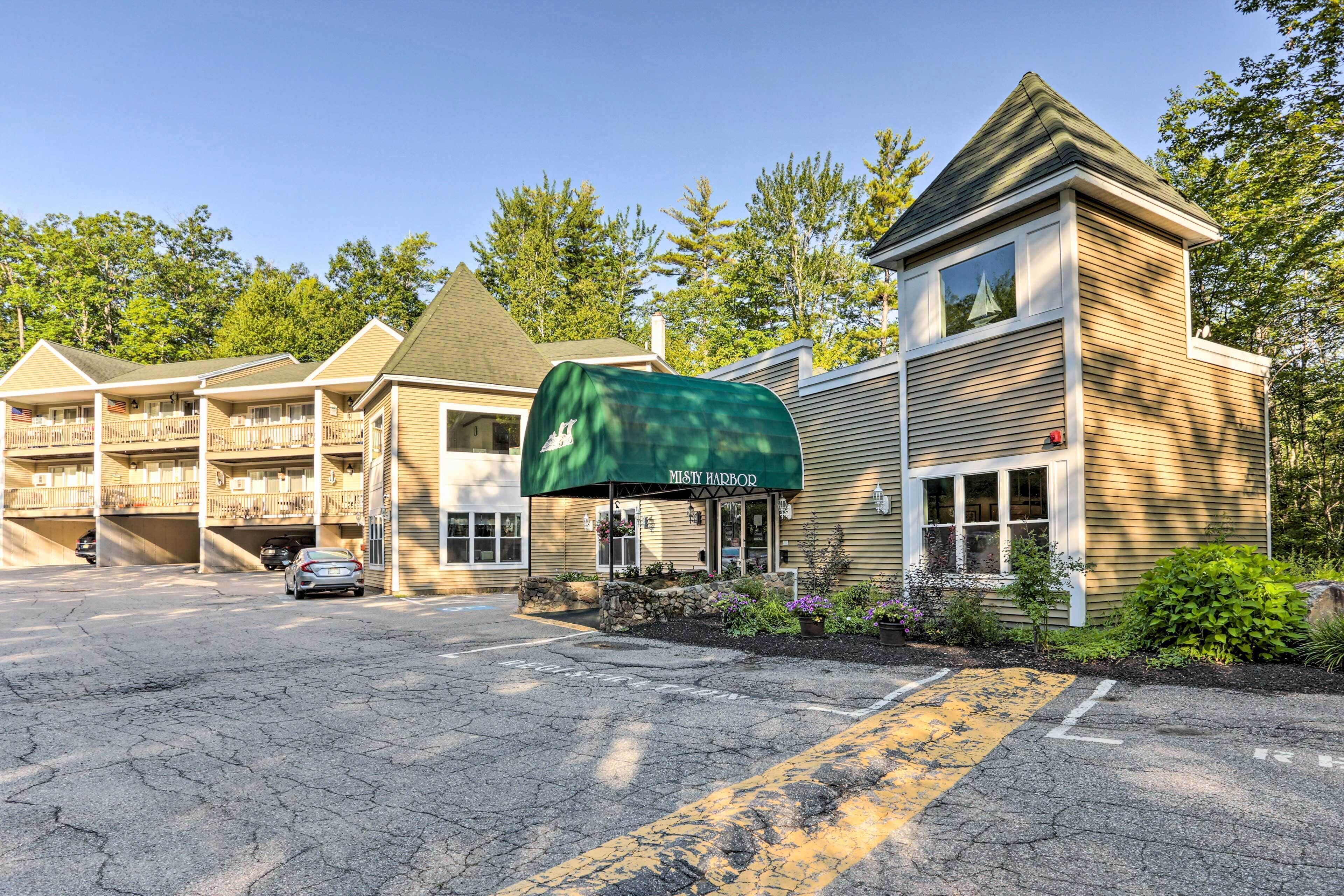 A motel with a green awning, multiple rooms, and a parking lot.