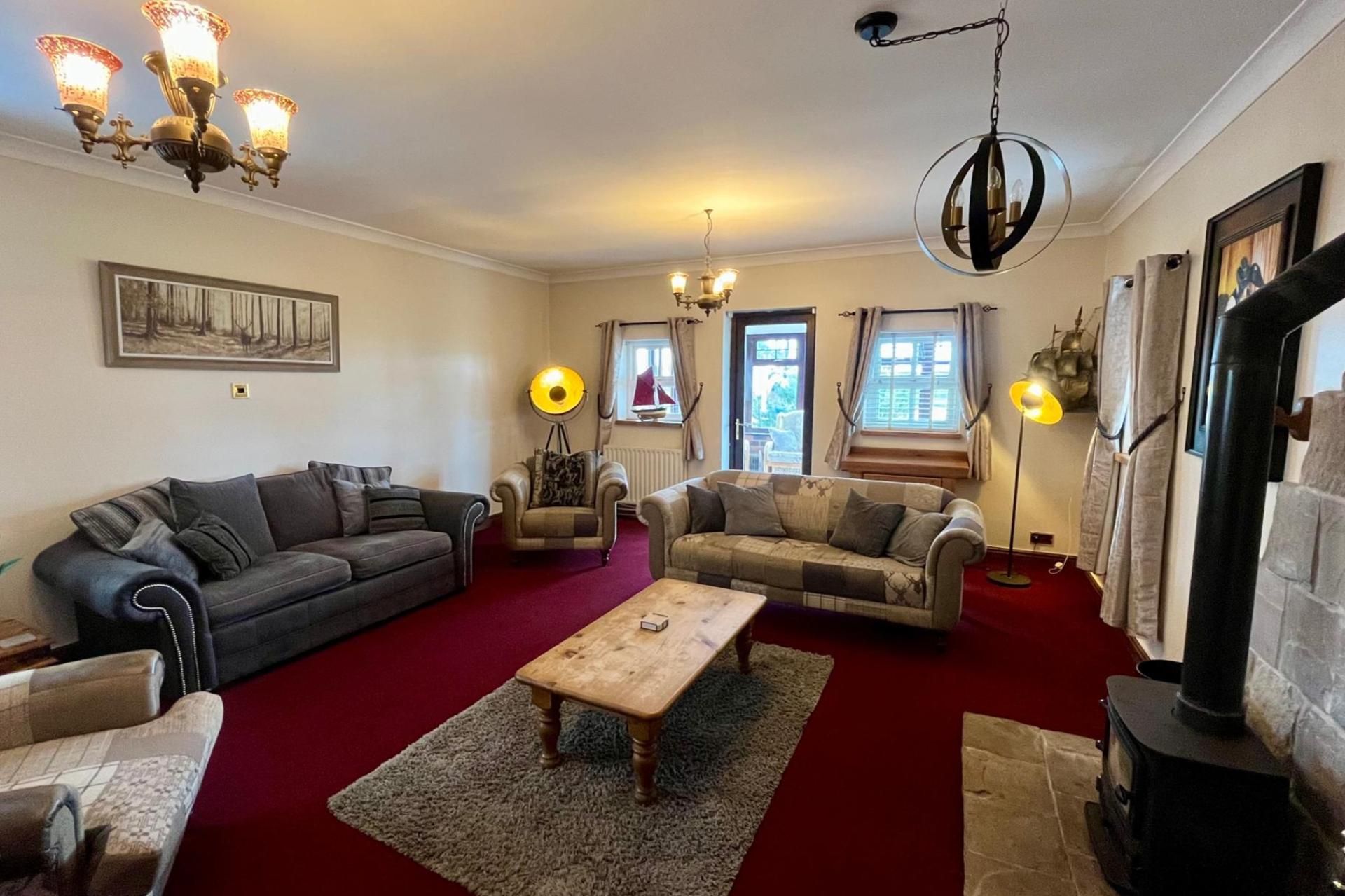 Een woonkamer met twee banken, een salontafel, een open haard en een kroonluchter.