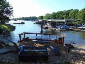 A riverside dock with a wooden deck, picnic tables, and chairs. - Swim Dock, Family Fun, Close to Hot spots! (Lake Ozark)