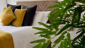 A bed with a tufted headboard, white bedding, and multiple pillows in yellow and black. - Apartment totally private entrance, sauna, shower, bedroom, studio,bathroom.     (Ballynahinch)