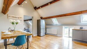 A spacious kitchen with a modern refrigerator, wooden beams, and a skylight. - Tadpole Cottage at Frog Hall (Tilston, near Malpas)