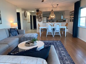 A living room with a sofa, a coffee table, and a dining area with a table and chairs.