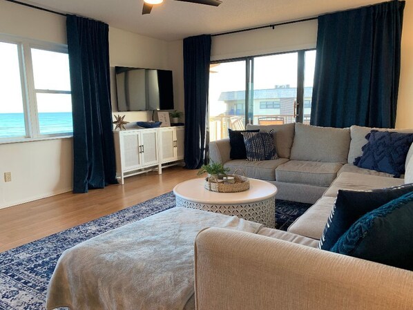 A living room with a sofa, a coffee table, and a view of the sea.
