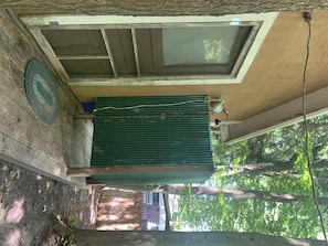 Enjoy the serene atmosphere of this tranquil outdoor space, featuring a covered area with a green door and a window above.