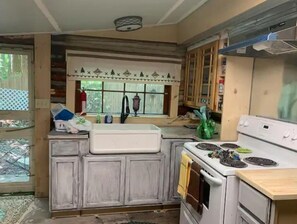 Enjoy cooking in this kitchen with a stove, sink, and cabinets, featuring a window above the sink and exposed wooden beams.