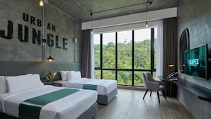 A hotel room with two beds, a desk, a TV, and a large window with a jungle view. - SCAPES Hotel (Genting Highlands)
