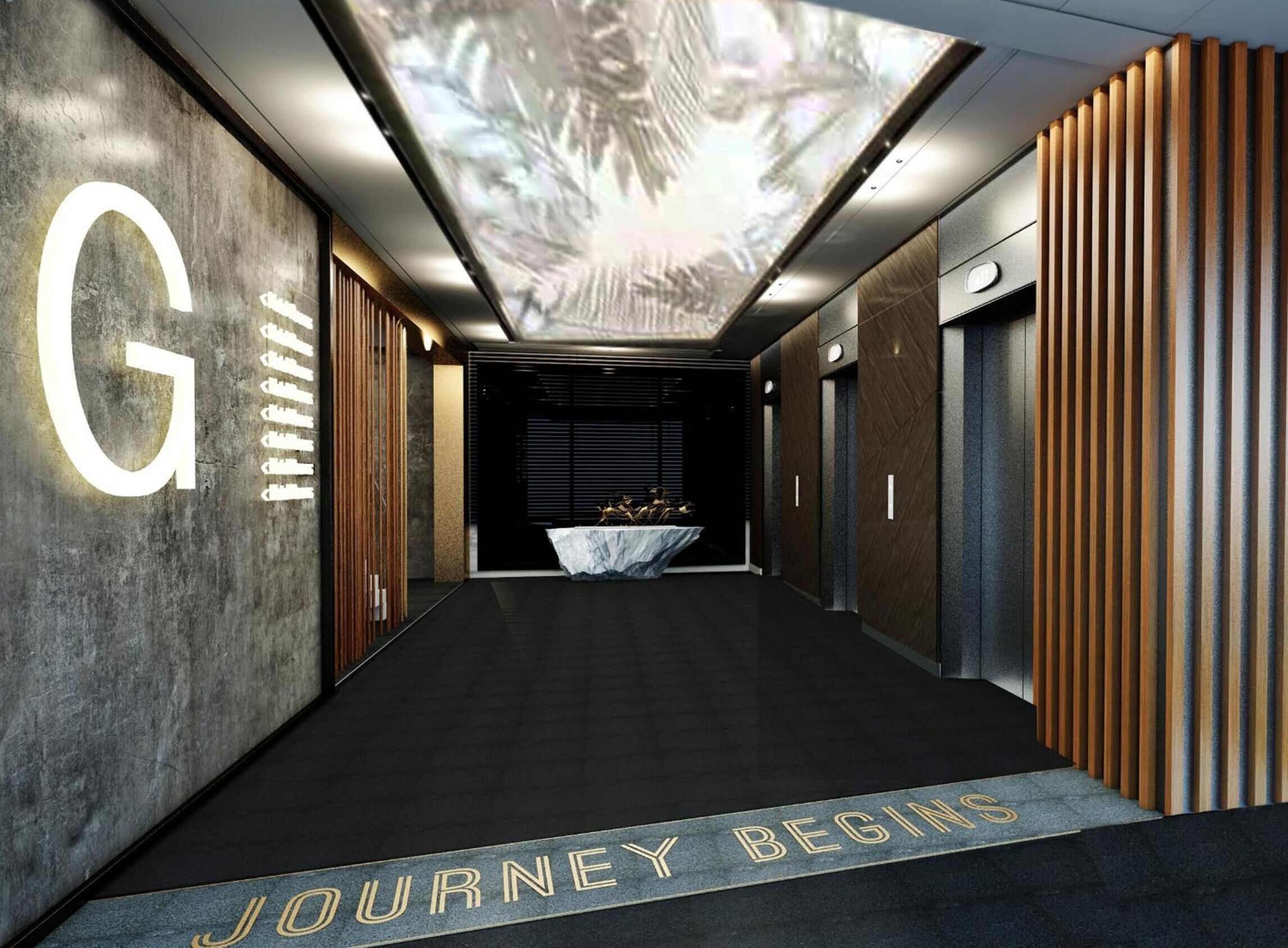 A modern hallway with a large illuminated 'G' on the left wall, a reception desk with a marble table in the center, and a 'JOURNEY BEGINS' sign on the floor.