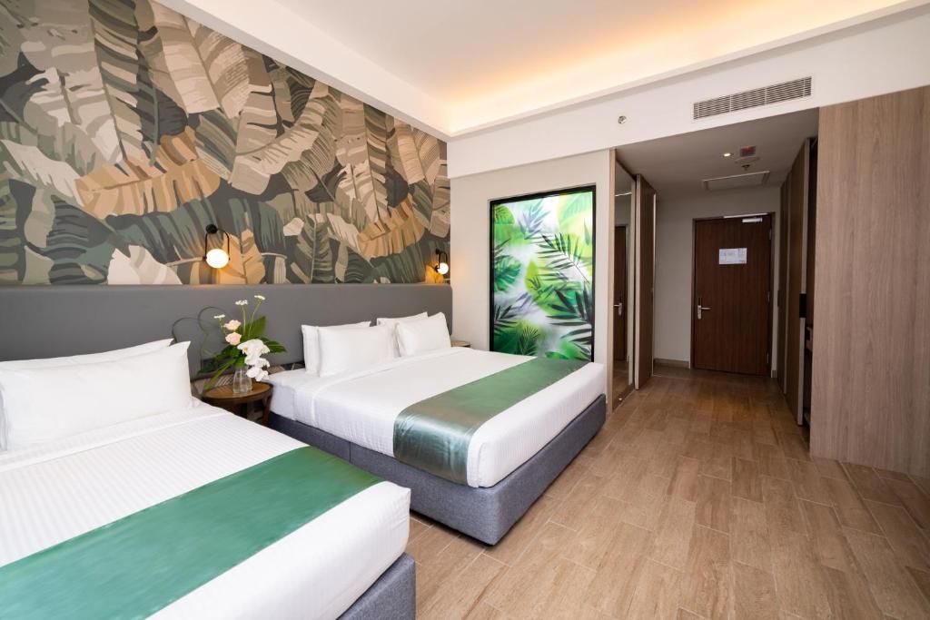 A hotel room with two beds, a large tropical leaf mural, and a view of a palm tree.