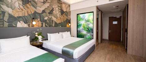 A hotel room with two beds, a large tropical leaf mural, and a view of a palm tree.
