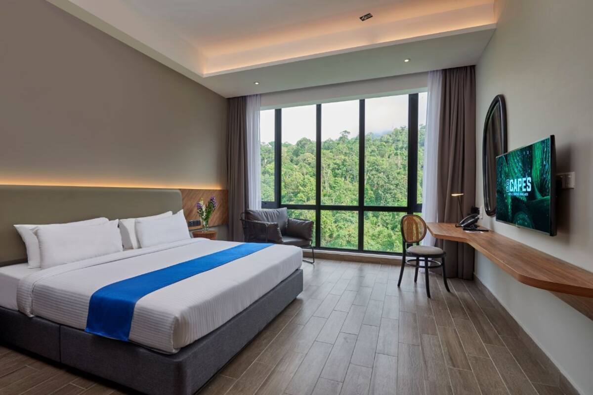 Una habitación de hotel moderna con una cama grande, un escritorio, una silla y un televisor en la pared.
