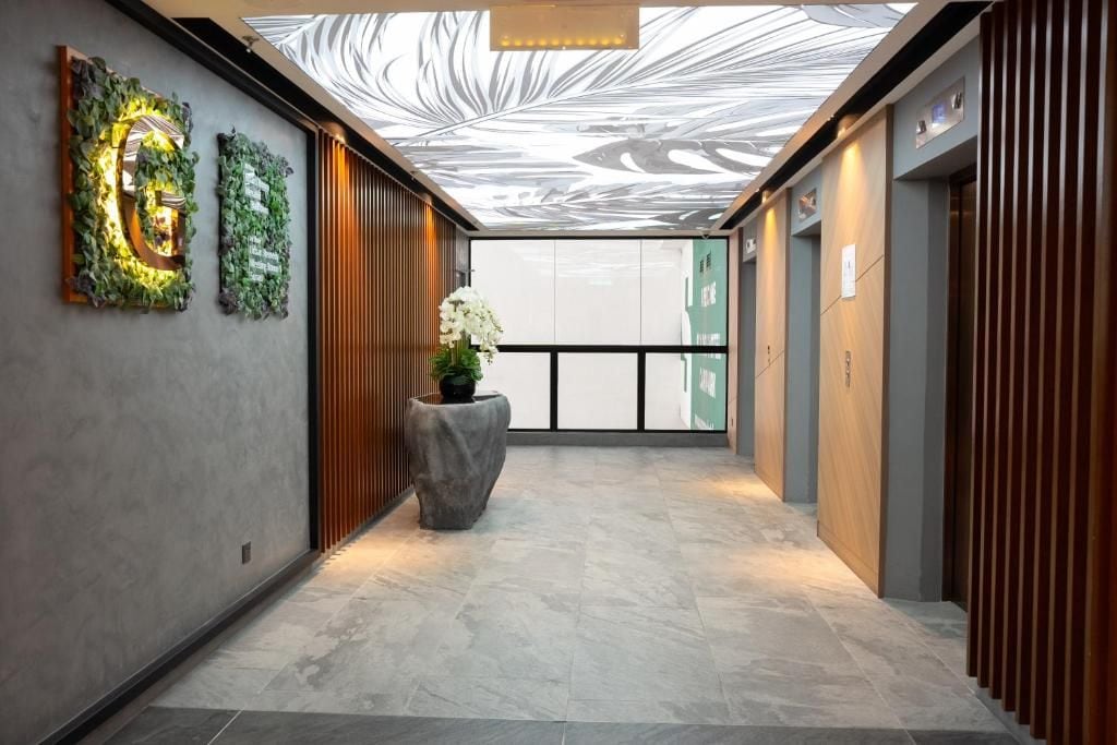 Un couloir moderne avec un décor au plafond, un comptoir d’accueil et une plante en pot.
