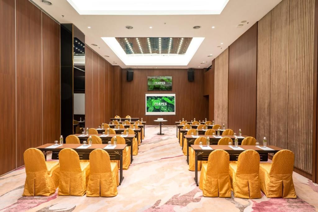 A conference room with a long table, yellow chairs, and a large screen at the front.